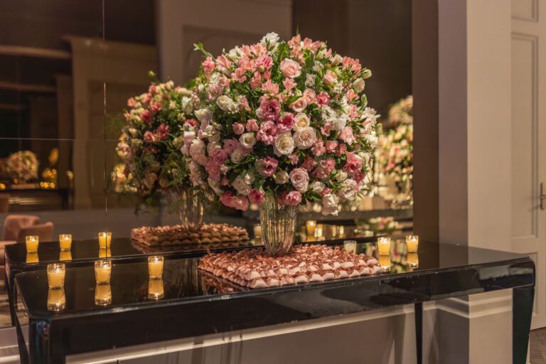 Luxurious floral bouquet with candlelight reflection on a polished table indoors.