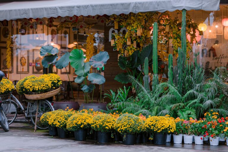 Cozy outdoor cafe surrounded by vibrant yellow flowers and lush green plants, creating a lively and inviting atmosphere.